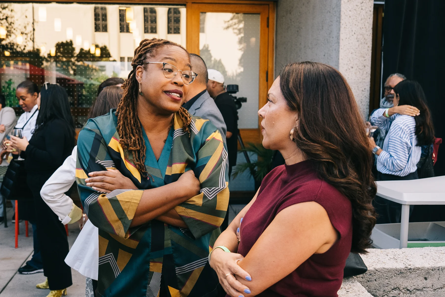 Two guests talk beside a standing table in the courtyard.
