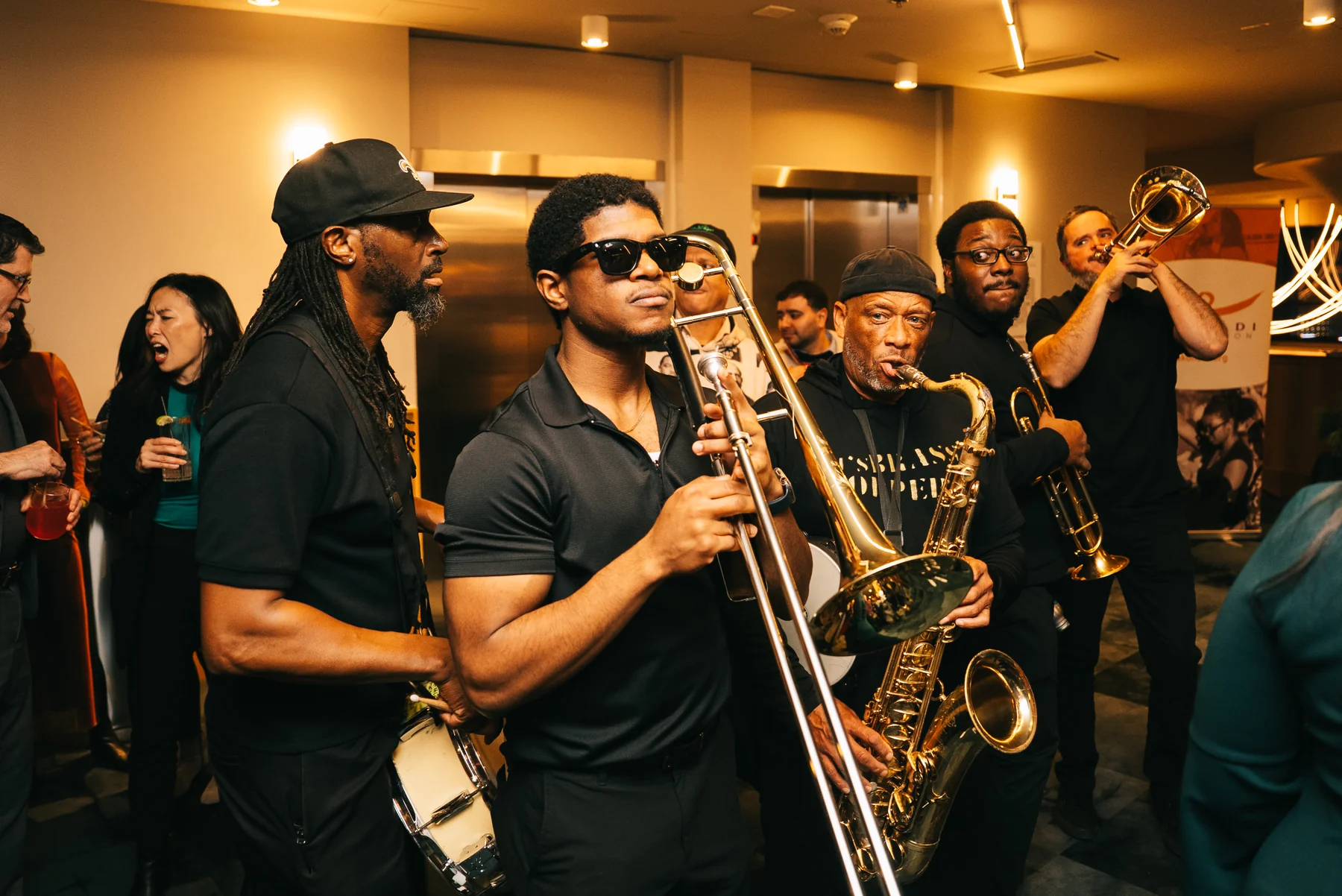 Brass musicians play among guests in a warmly lit room.