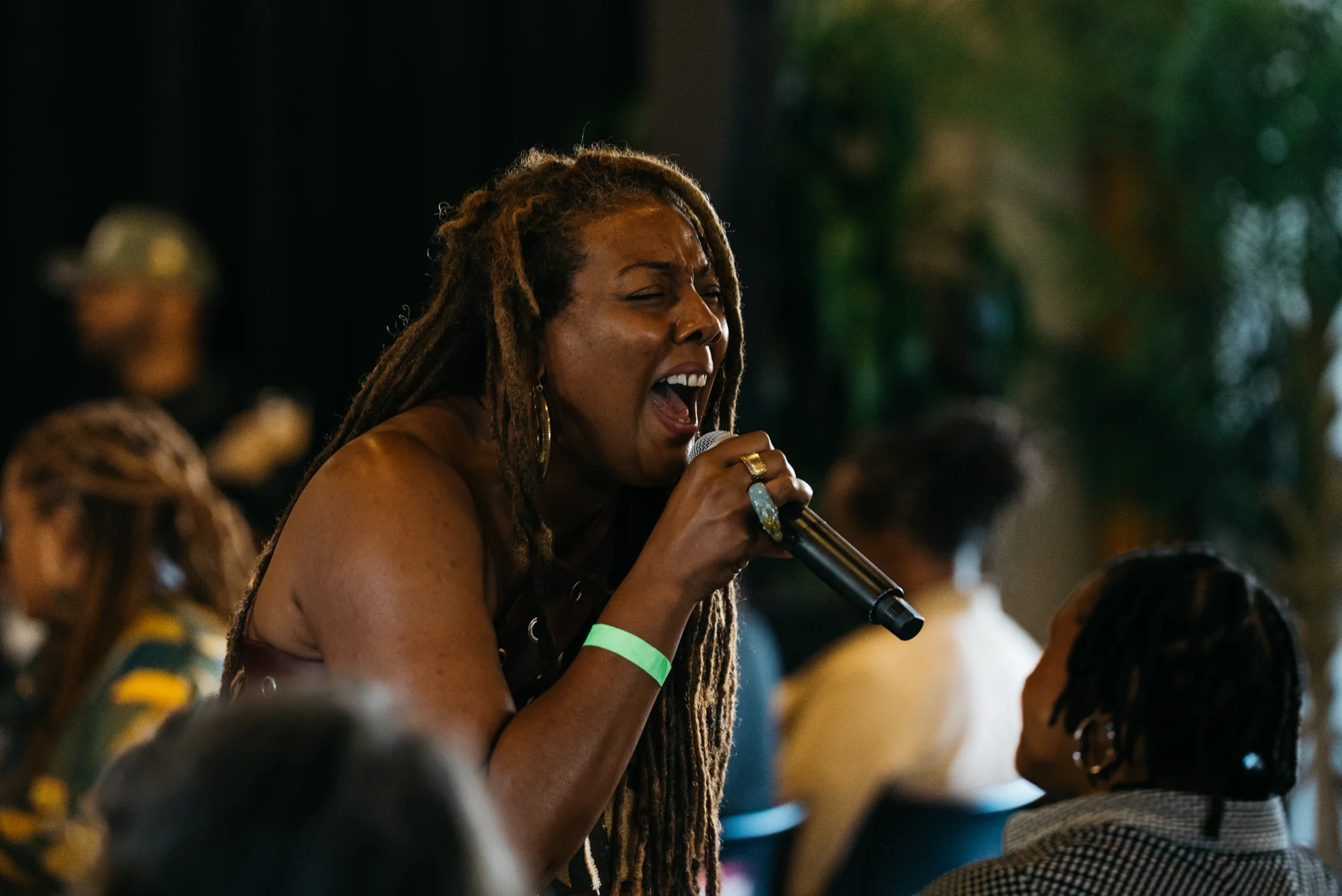 A vocalist performs with a handheld microphone among seated guests.