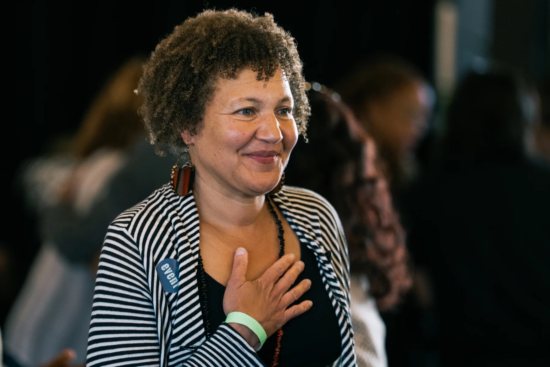 A guest smiles with a hand resting on their chest during the event.