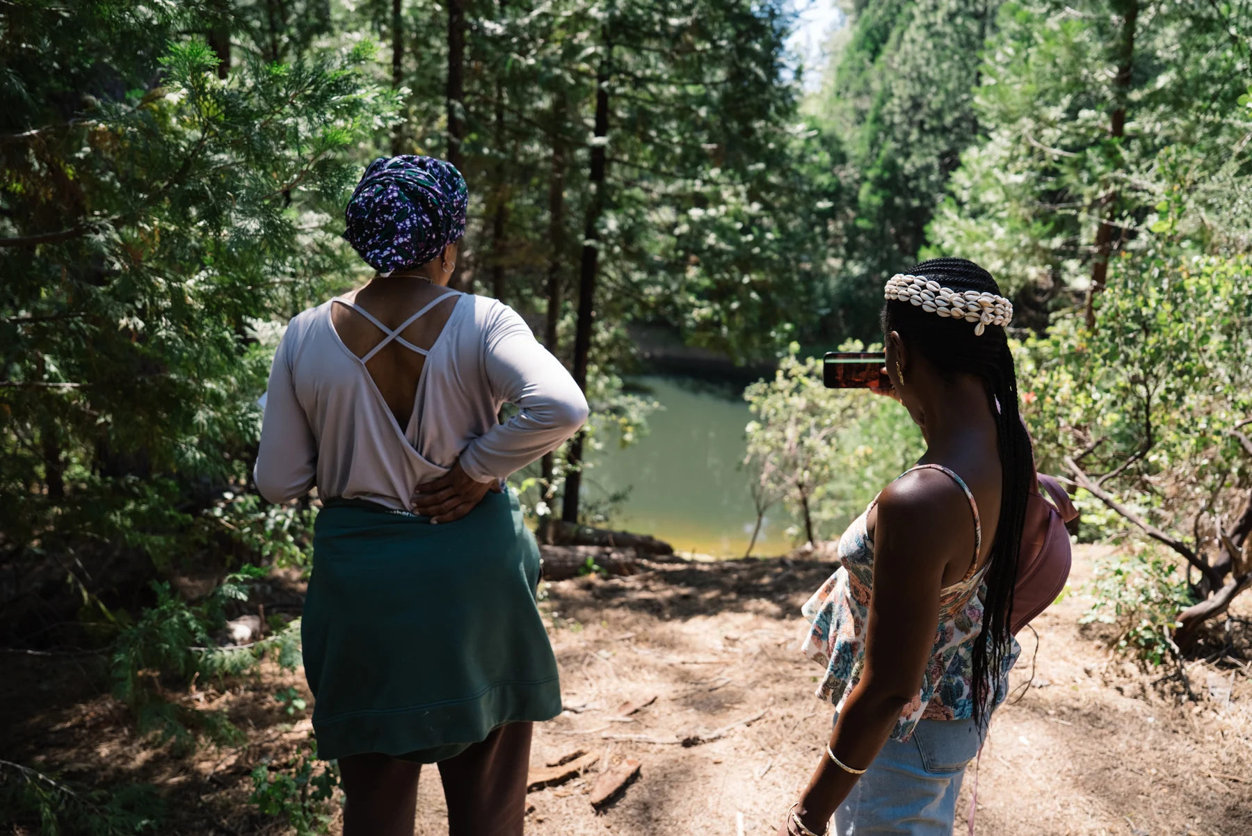 Two participants pause on a wooded path to look across the lake during the land tour.