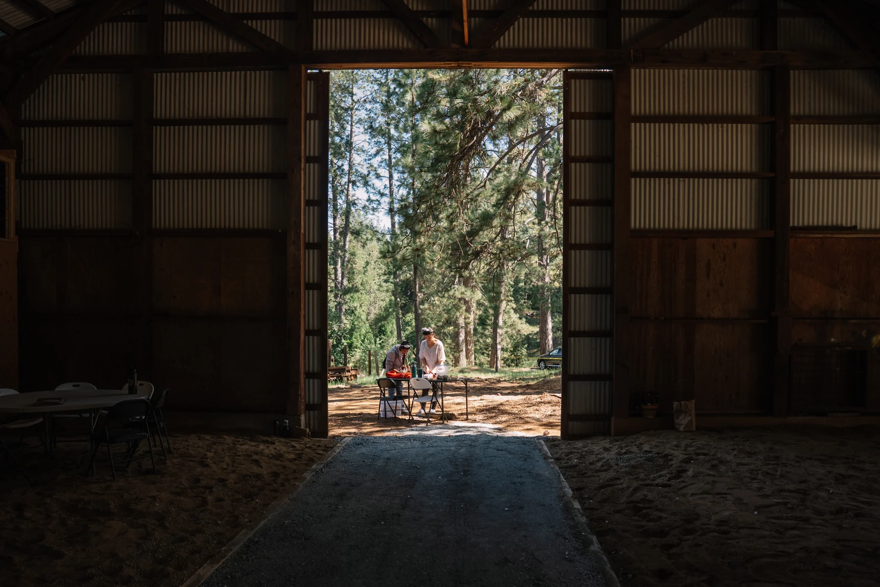 Two people at an outdoor table seen through the open doorway of a timber-framed building.
