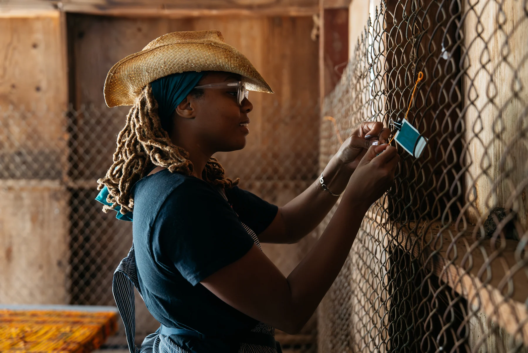 A participant clips an instant photograph to a line along a wire wall.
