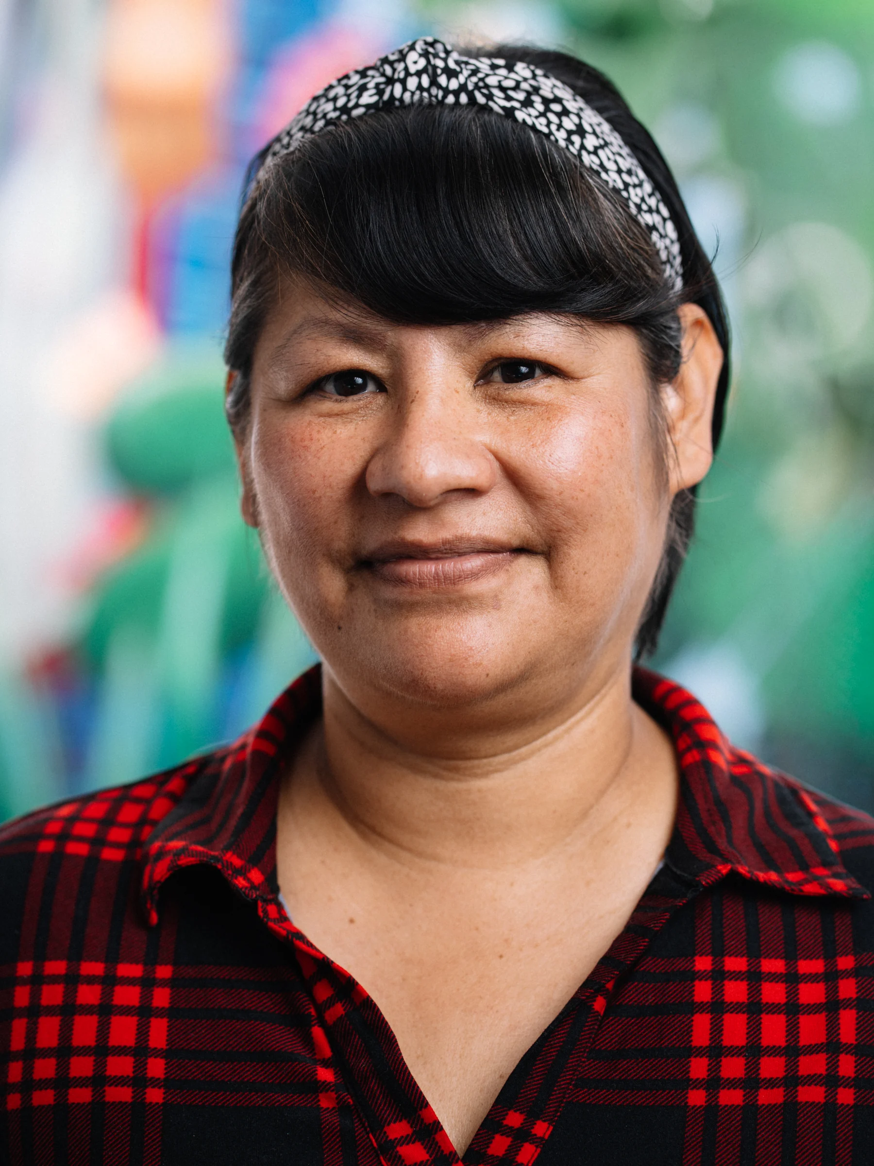 A subject in a red plaid shirt and patterned headband looks toward the camera.