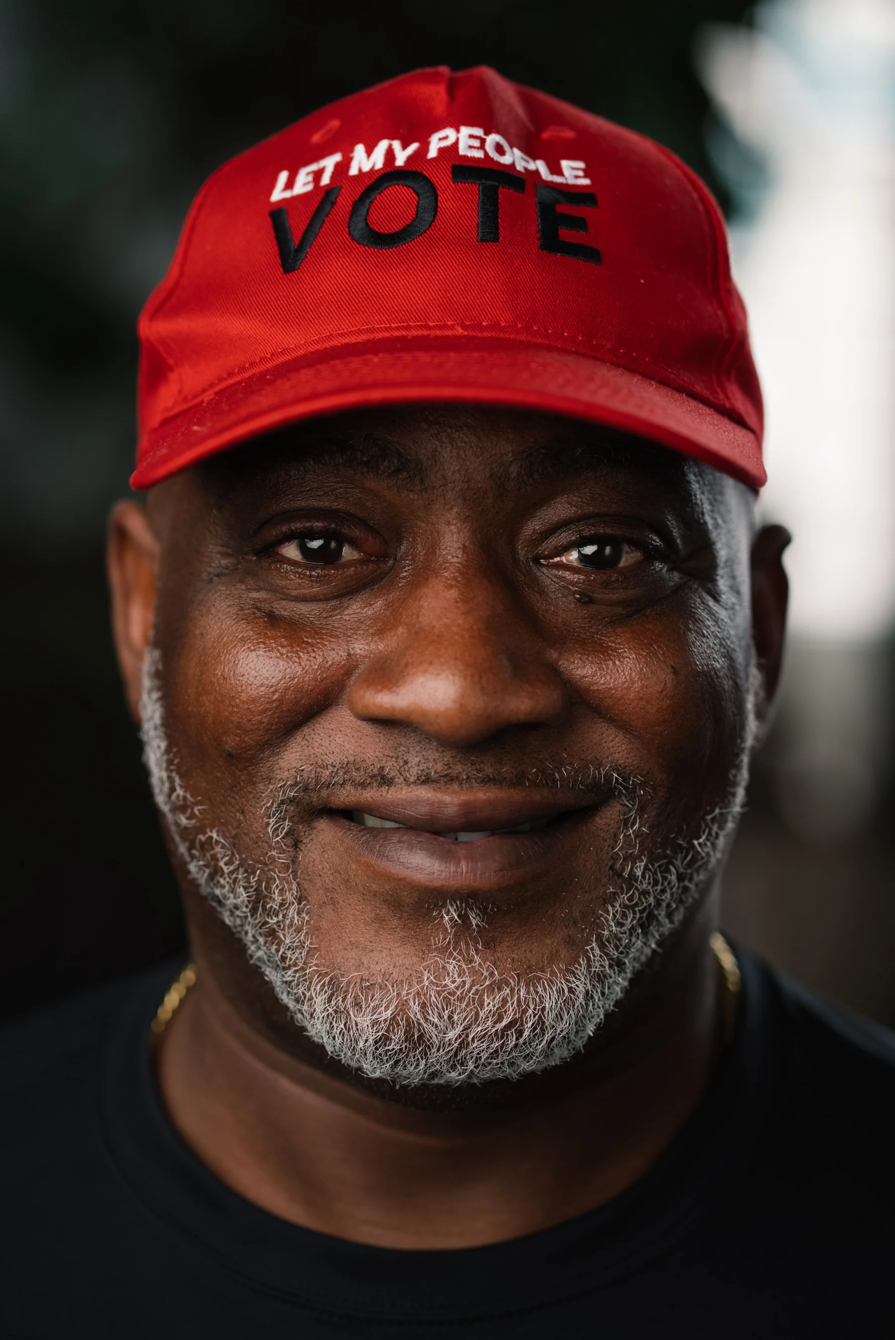 Live Free USA headshot: Smiling subject wearing a red voting cap.