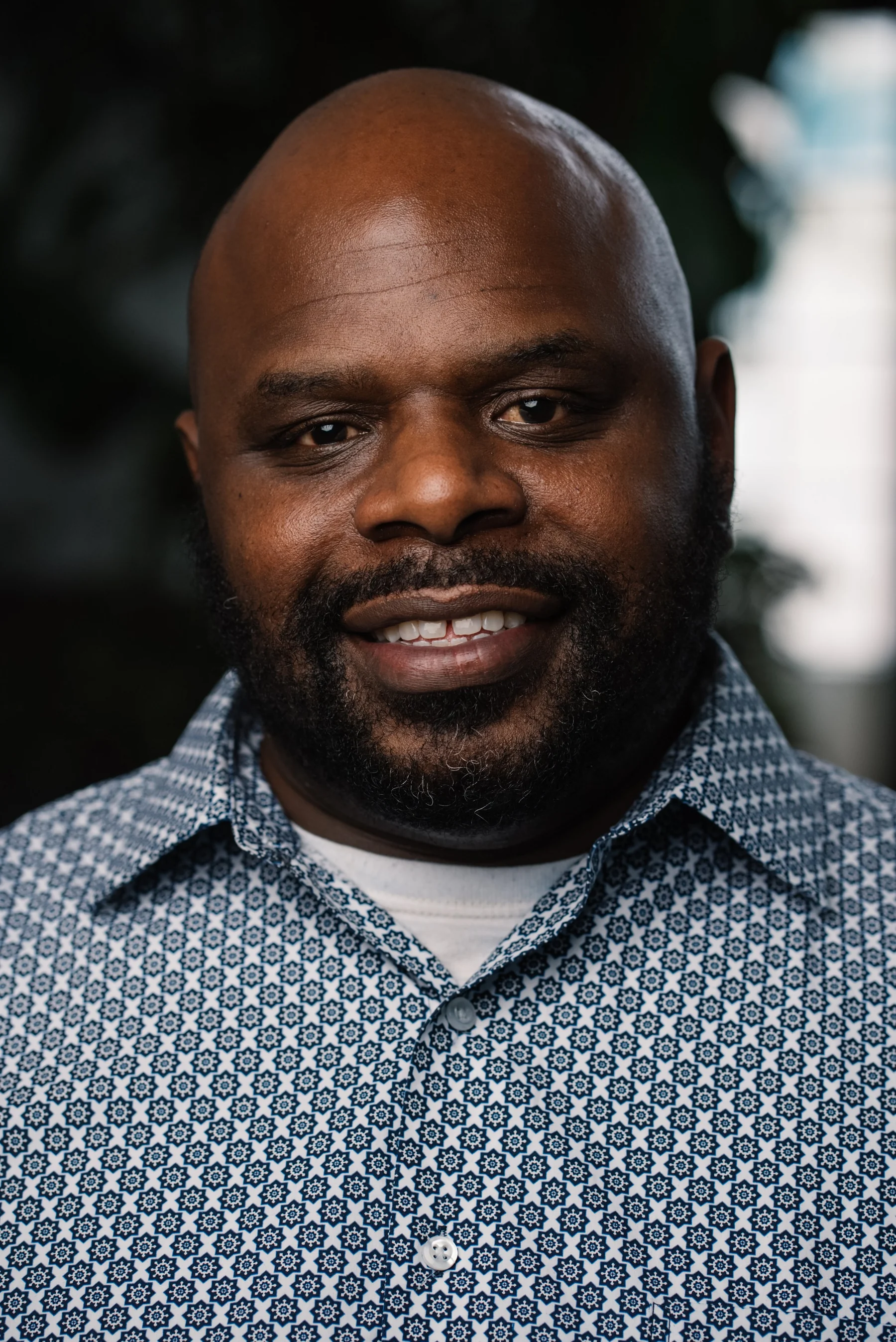 Live Free USA headshot: Smiling subject wearing a patterned blue and white shirt.