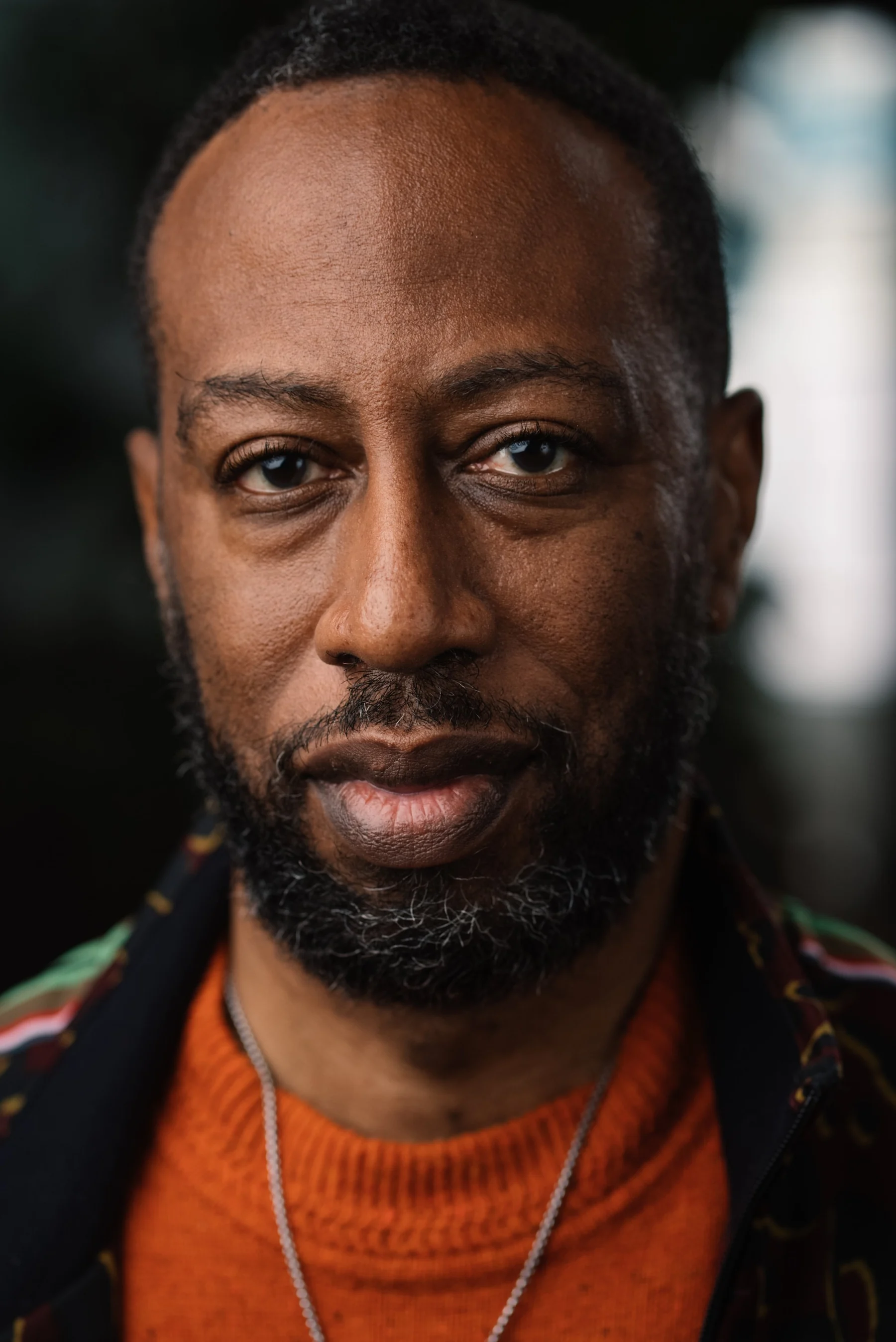 Live Free USA headshot: Subject wearing an orange sweater and layered necklaces.