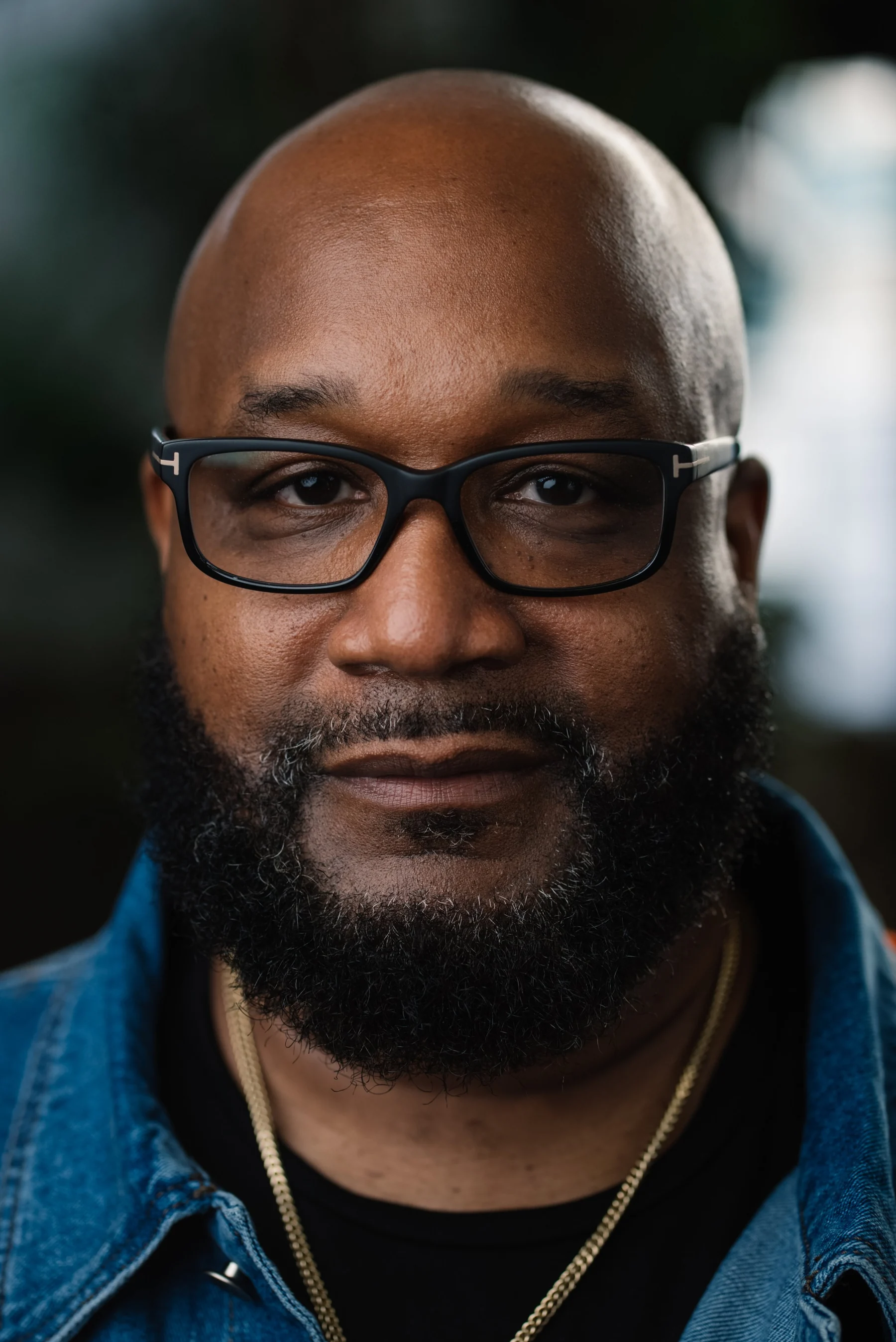 Live Free USA headshot: Subject wearing dark glasses and a blue denim shirt.