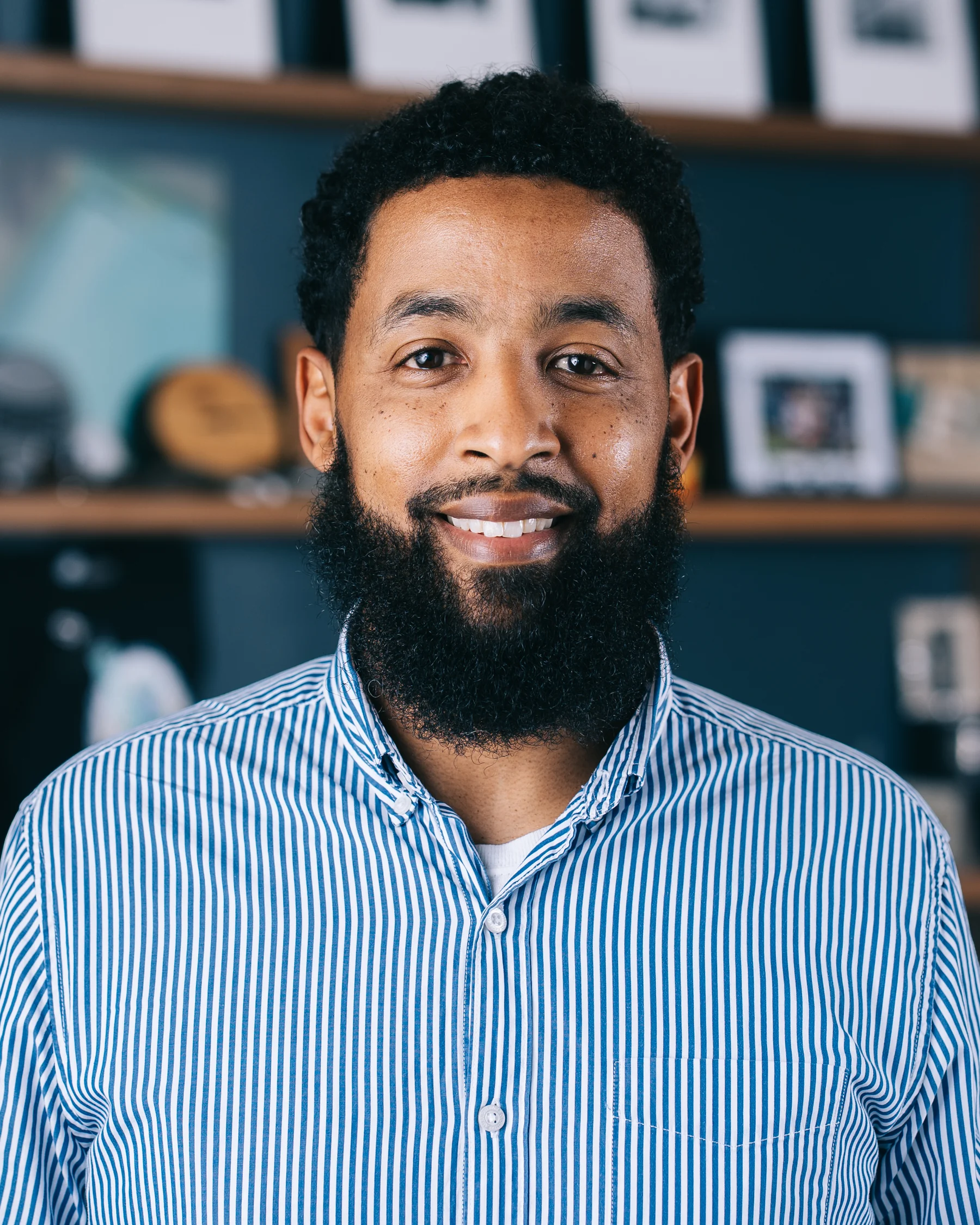 A participant with a beard wearing a blue striped shirt looks toward the camera.