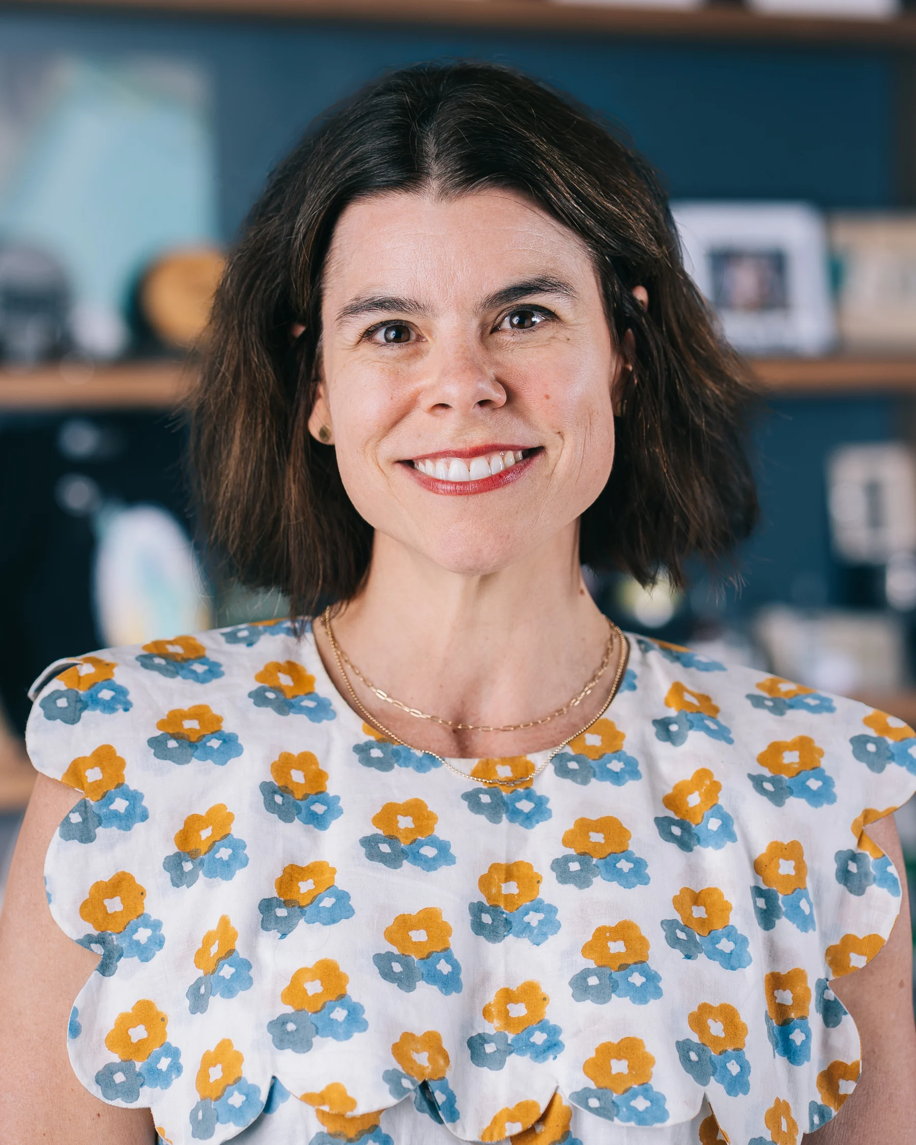 A smiling participant in a floral top photographed against softly blurred shelves.