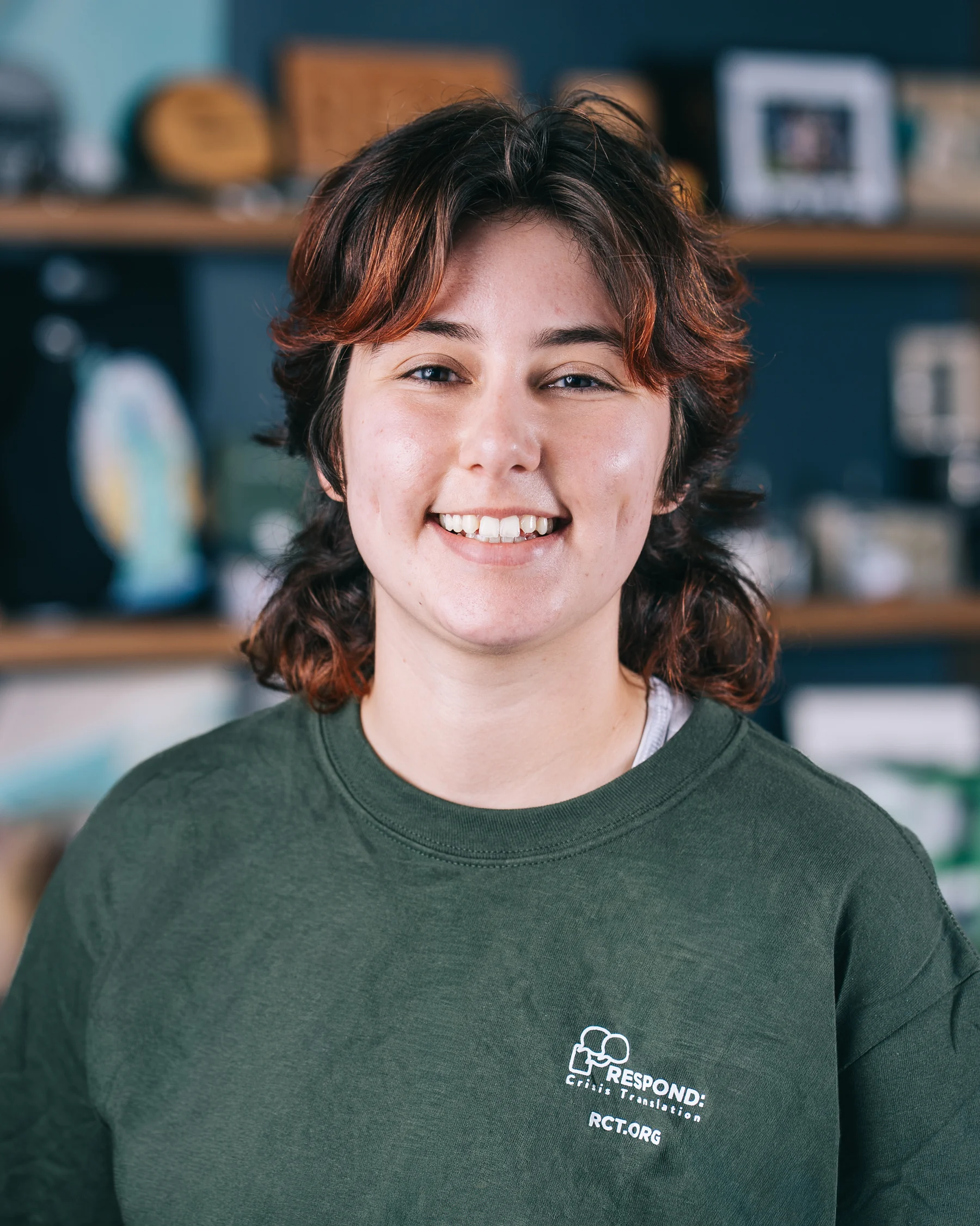 A smiling participant in a dark green shirt photographed in front of display shelves.