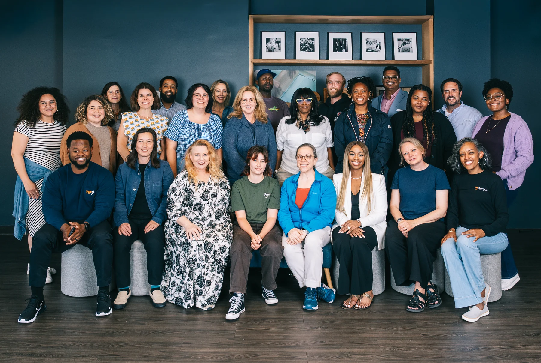 The 2026 Accelerator group poses together in two rows in front of dark teal shelving.