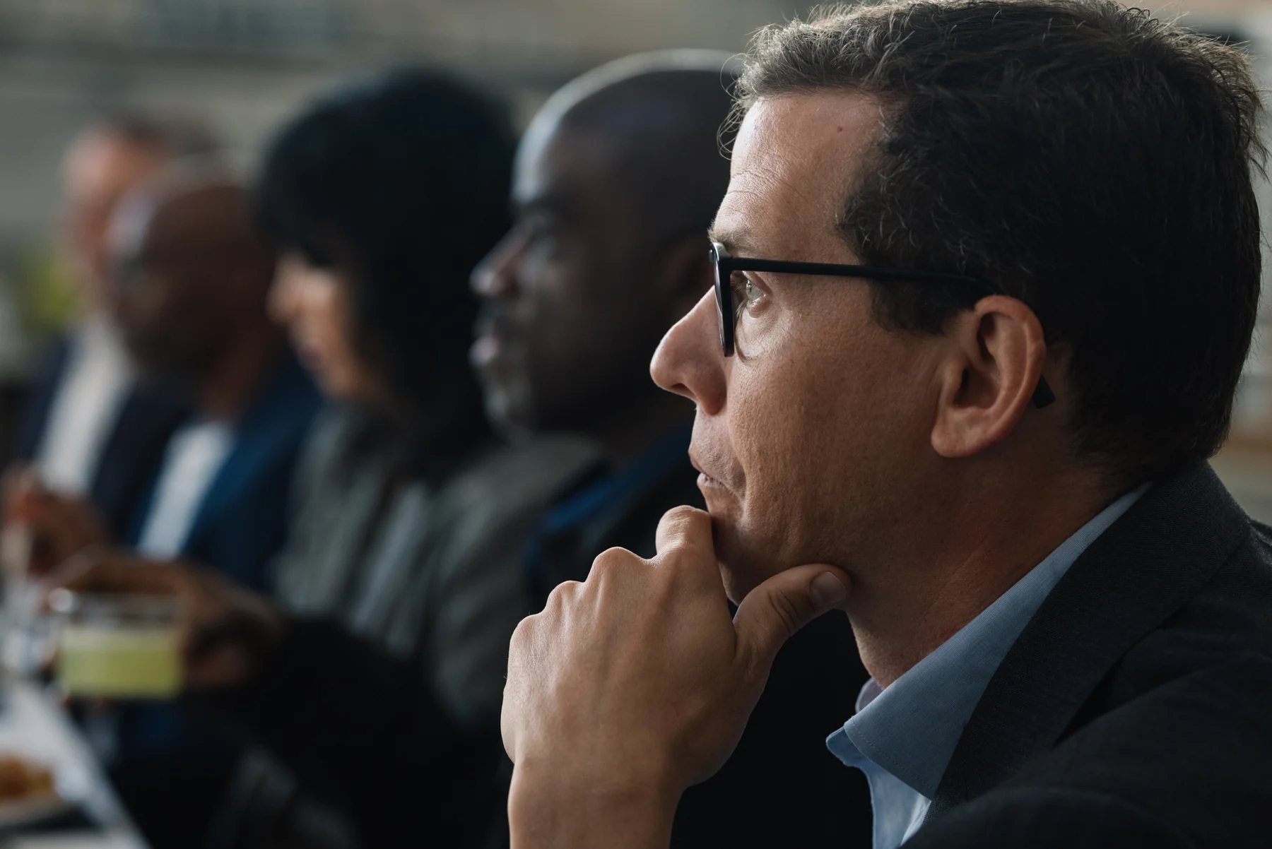 A guest wearing glasses listens closely at a Redefine Alliance gathering.
