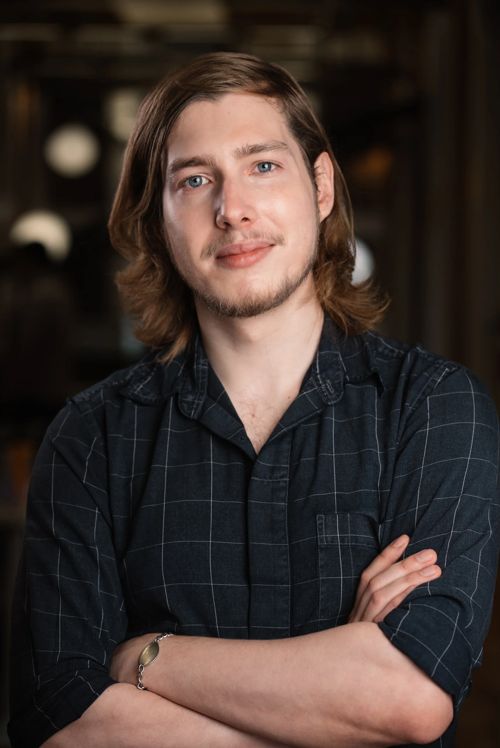 Searchlight team member with arms crossed in a dark plaid shirt.