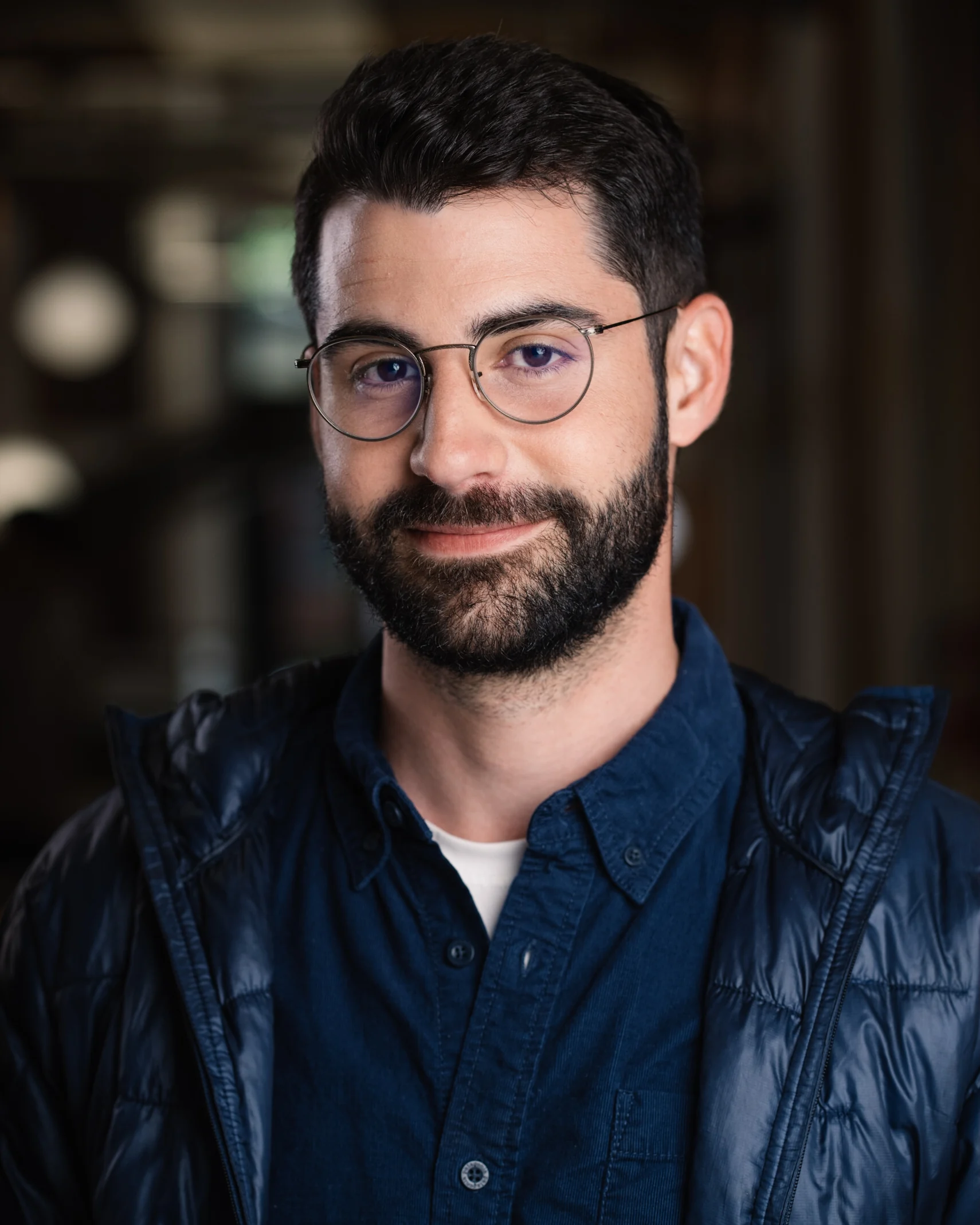 Searchlight team member wearing glasses and a dark overshirt.