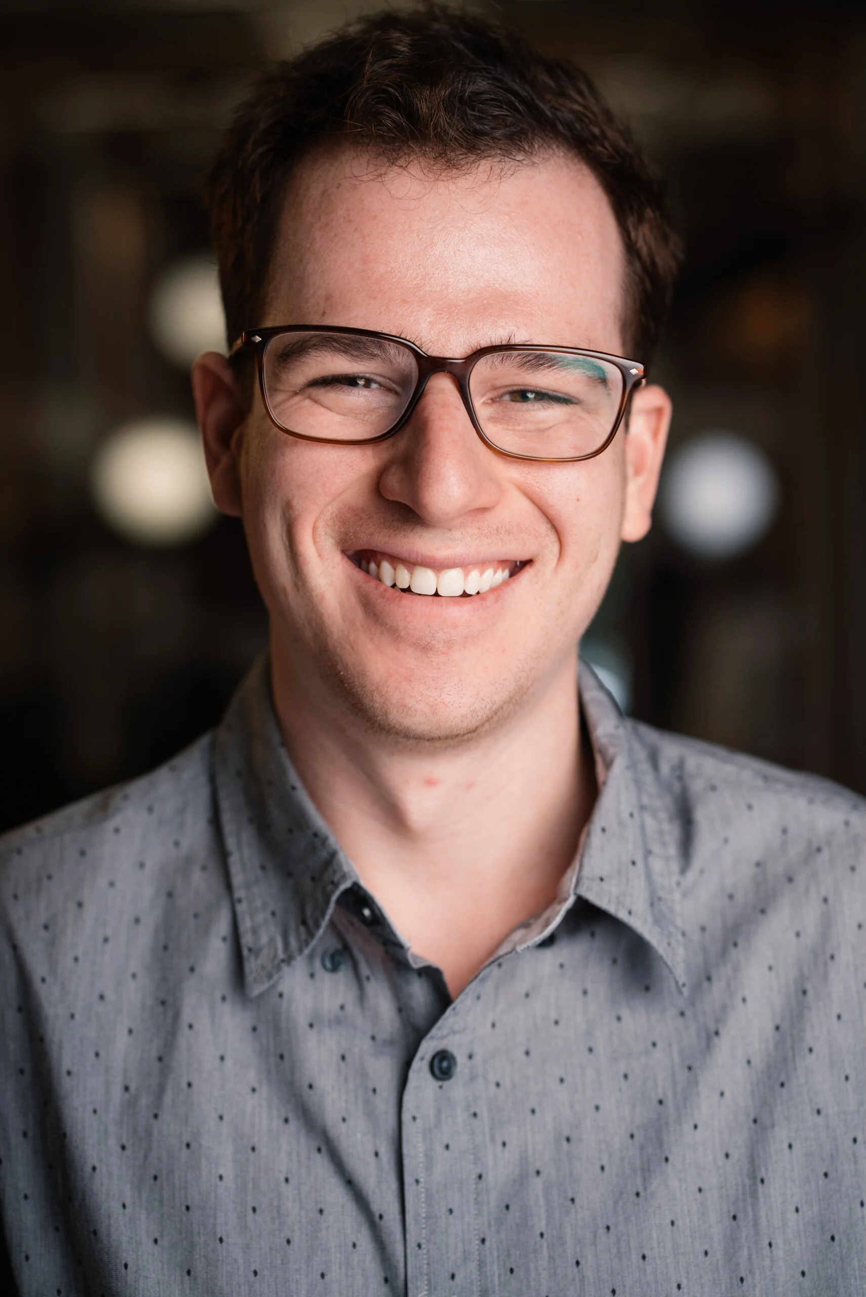 Smiling Searchlight team member in glasses and a gray shirt.