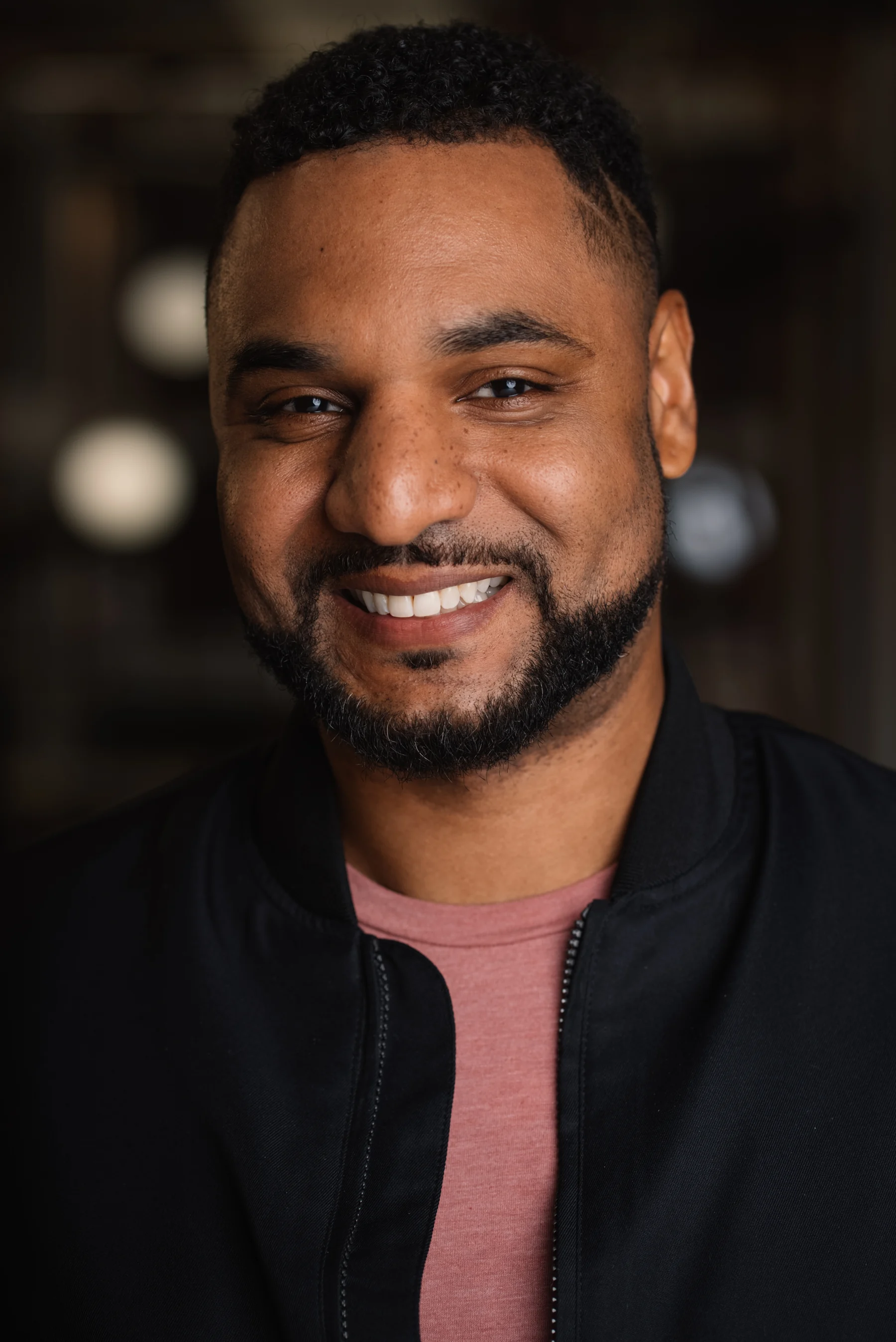 Searchlight headshot with a dark jacket and burgundy shirt.
