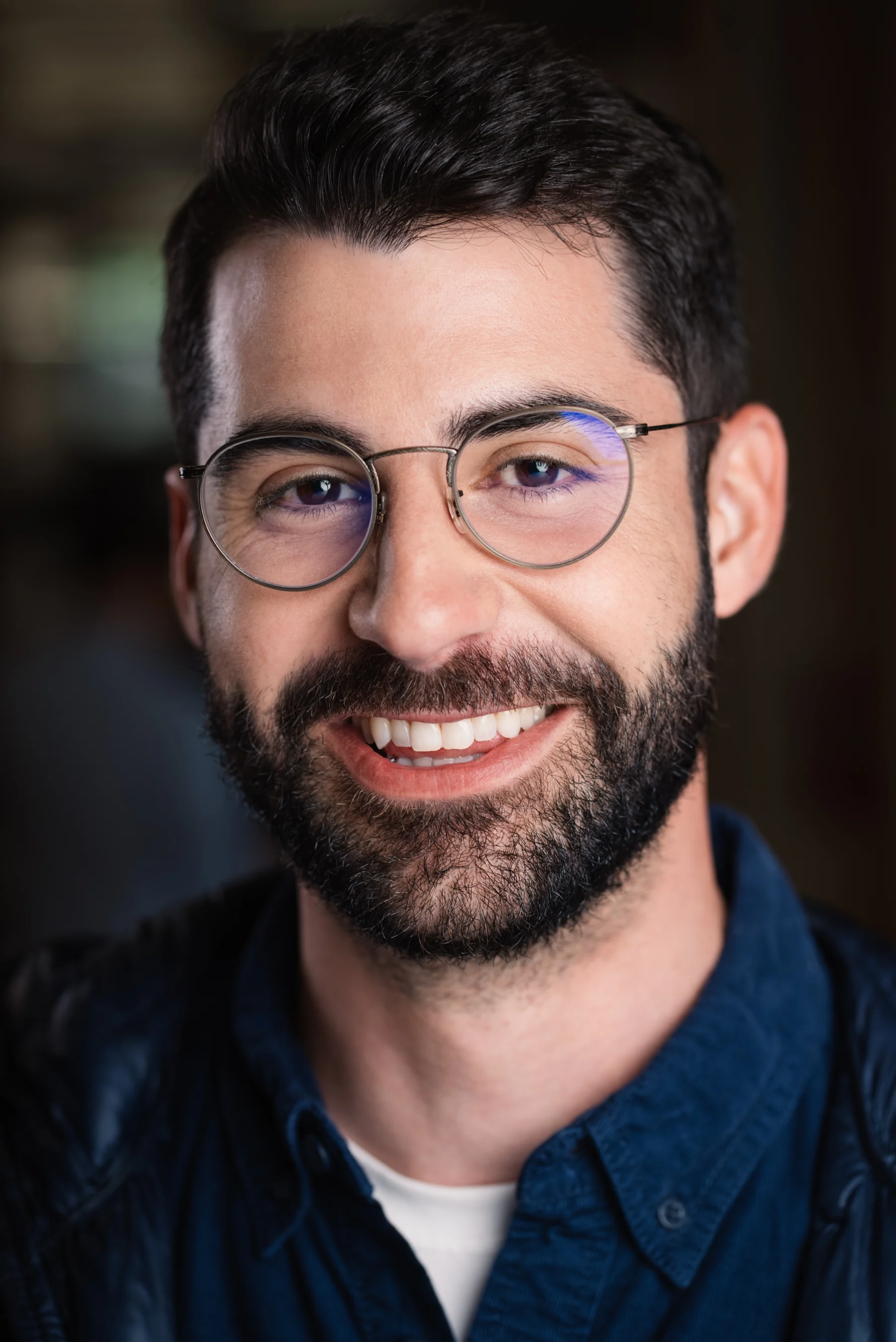 Smiling Searchlight team member in glasses against a softly blurred background.