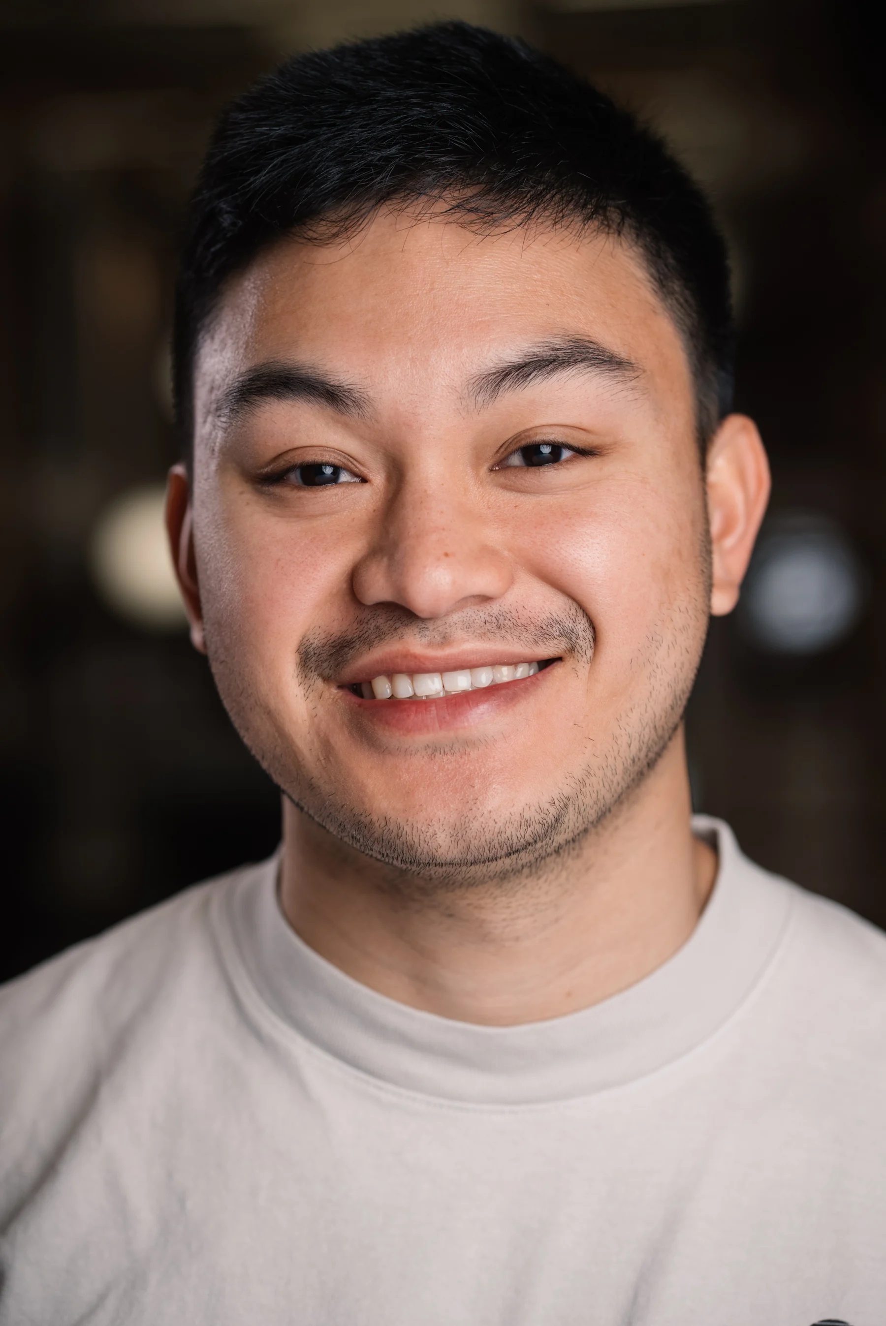 Searchlight headshot with a light shirt against a dark background.