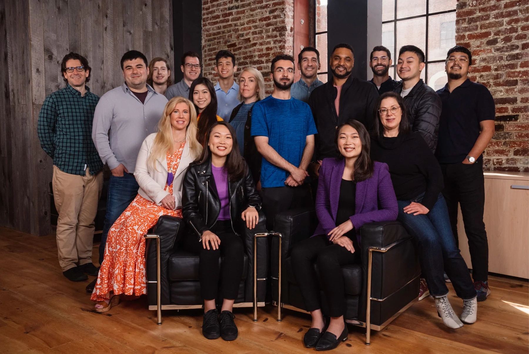 Searchlight's team gathered for a group portrait in a brick-walled workspace.